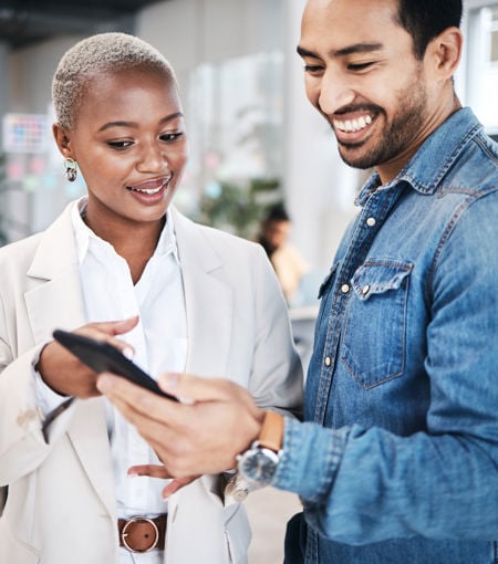 male and female in office looking at mobile phone screen